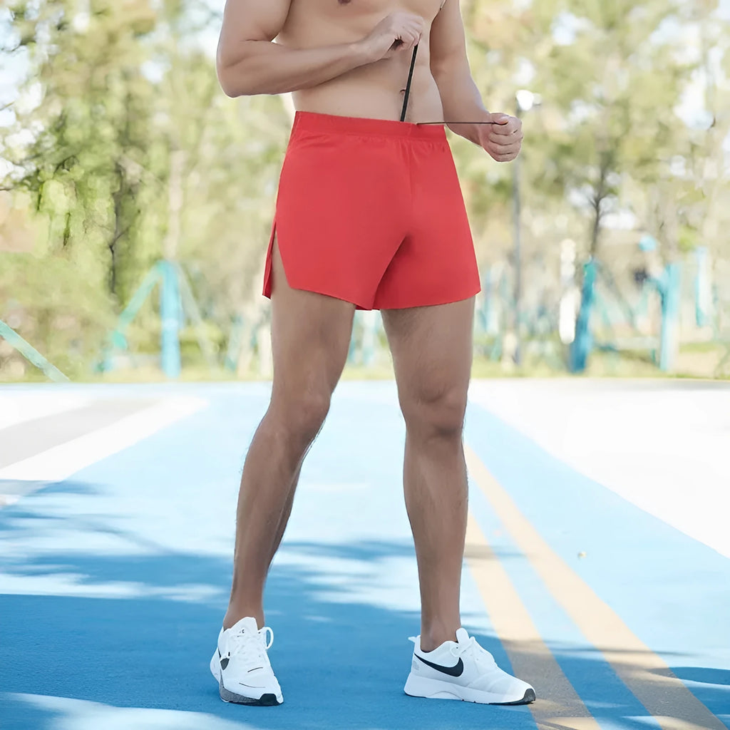 Man wearing red high-waisted loose-fit off-road running shorts during a cross-country run.