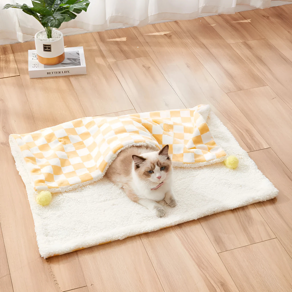 Plush pet blanket with plaid pattern and fur ball decoration for cats and dogs on sofa