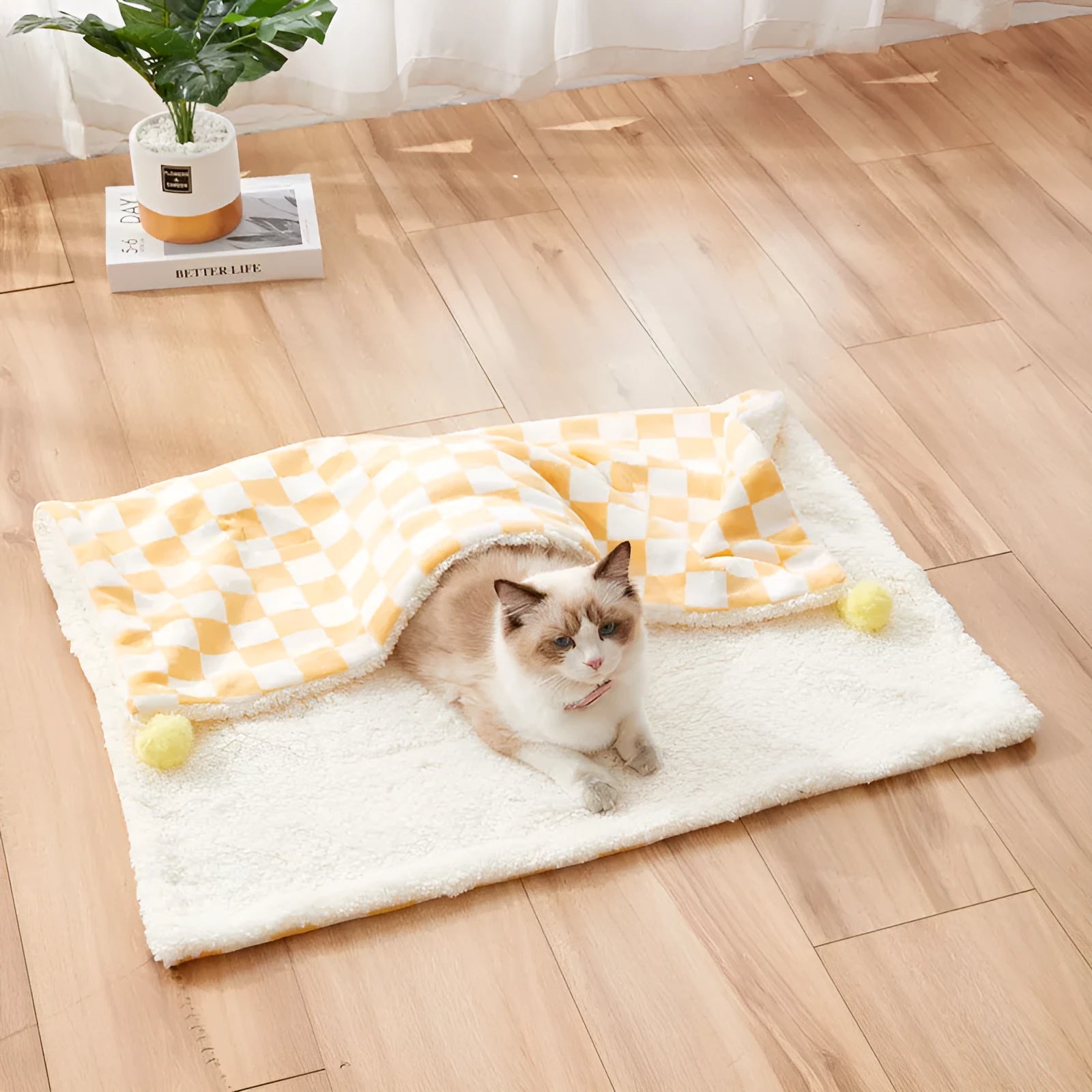 Plush pet blanket with plaid pattern and fur ball decoration for cats and dogs on sofa