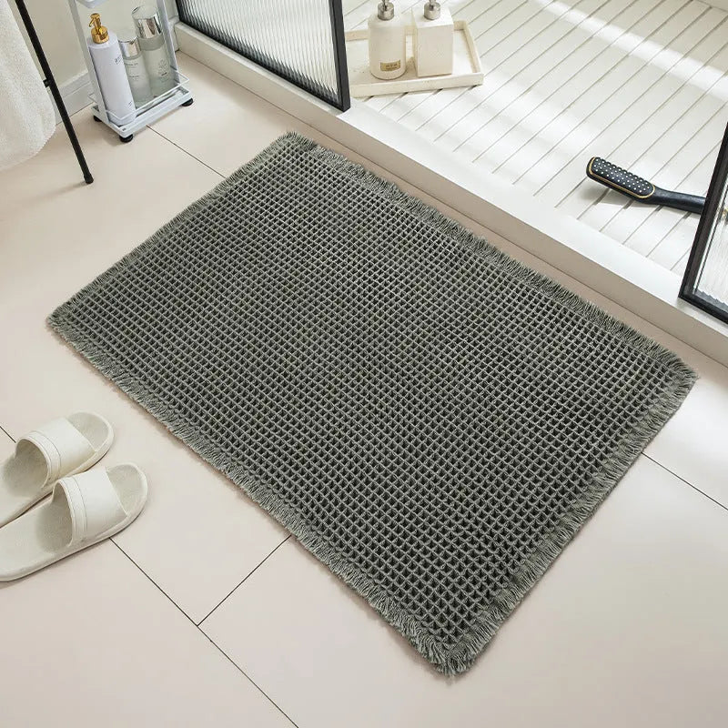A beige checkered non-slip polyester bathroom carpet on a tiled floor.
