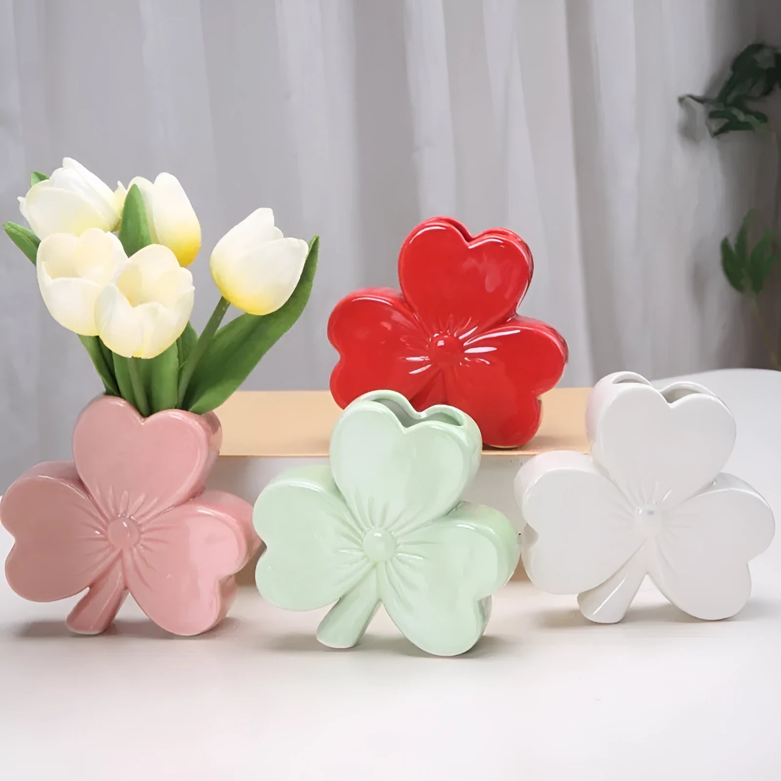 Square white porcelain clover ceramic vase on a desk, shown in light green colour.