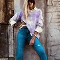 Lilac plaid print loose women's sweater with ribbed collar and cuffs on a hanger.