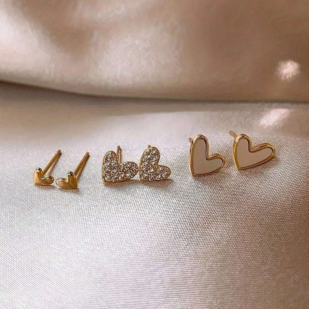 Set of three pairs of heart-shaped alloy earrings in gold, black, black and white, and pink colours