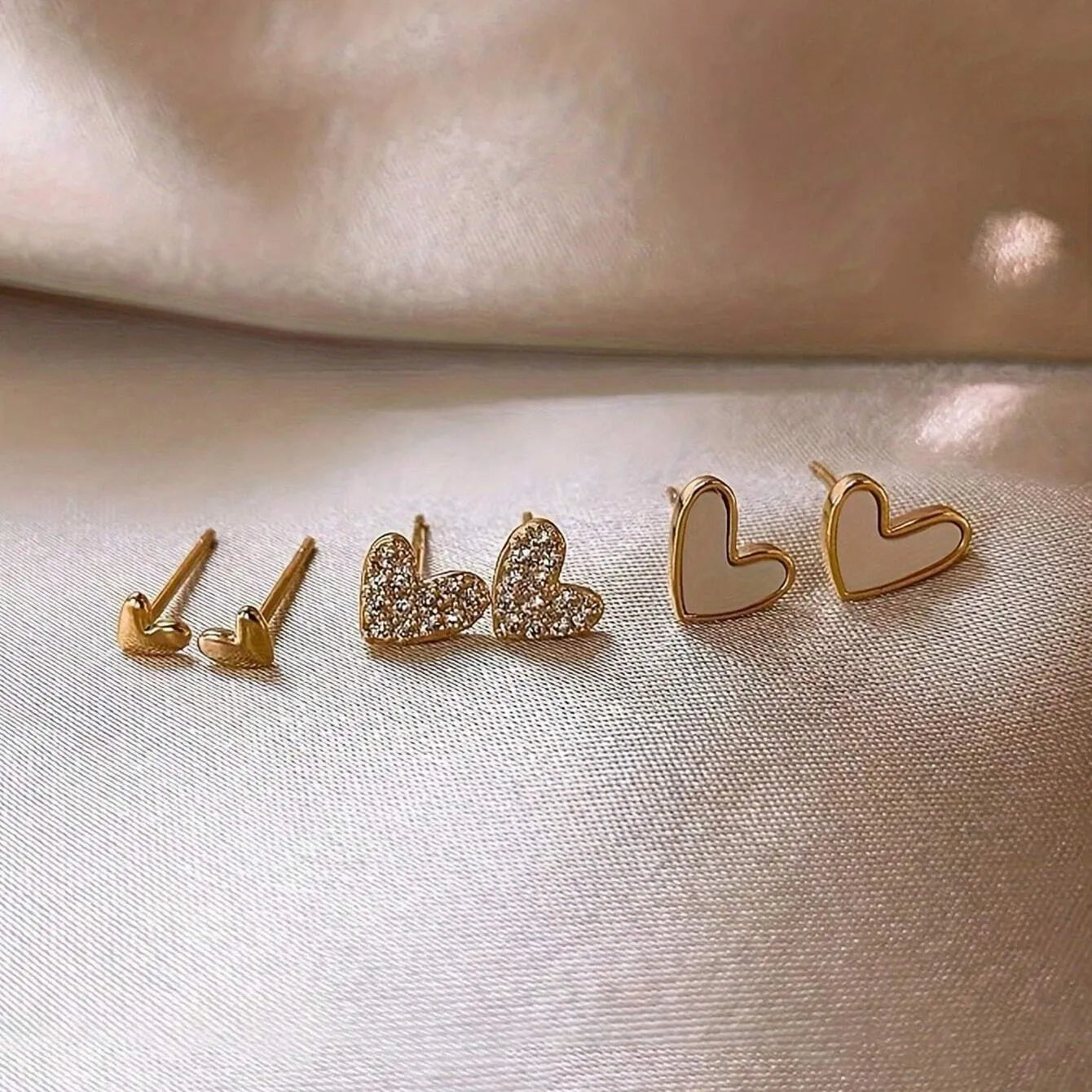 Set of three pairs of heart-shaped alloy earrings in gold, black, black and white, and pink colours