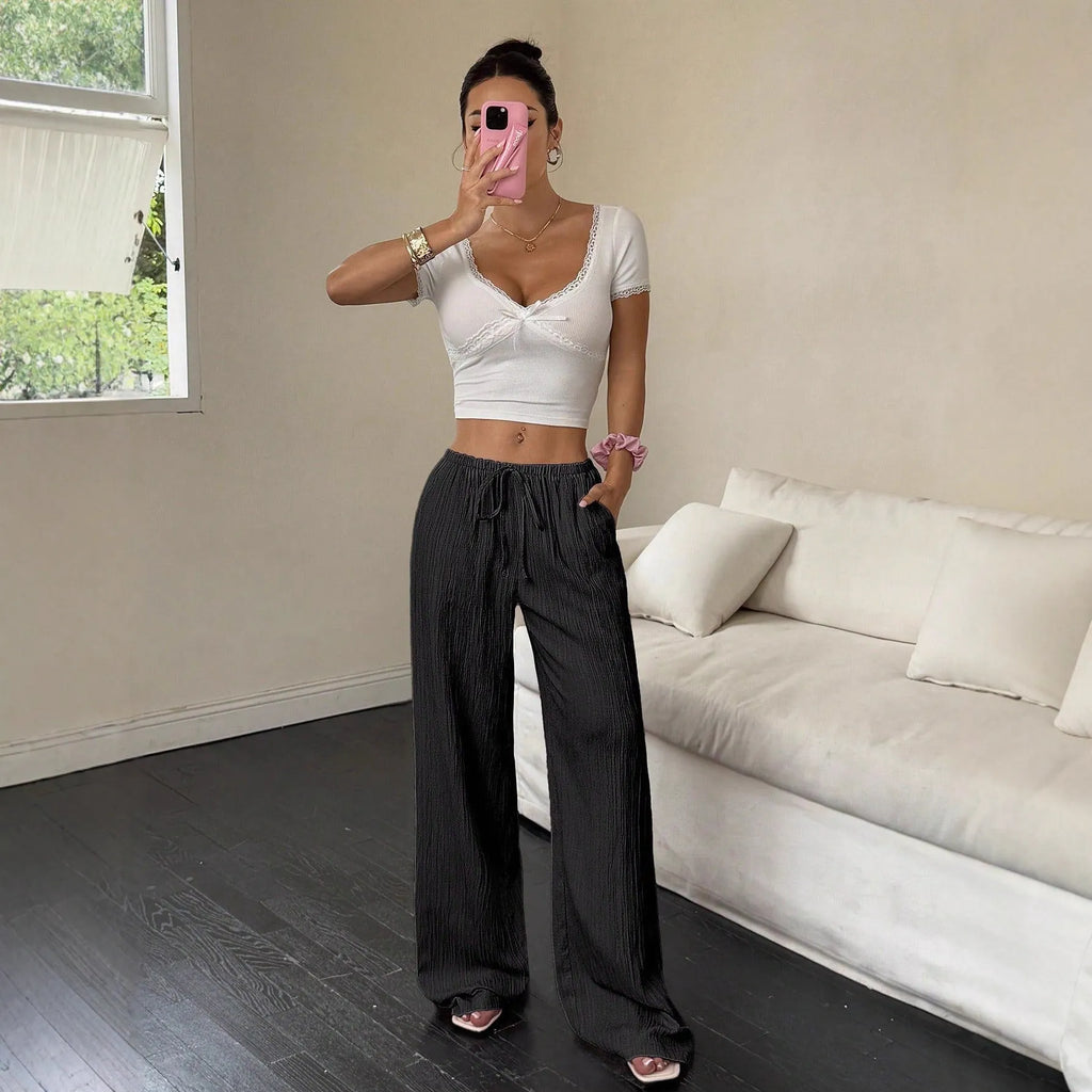 Women's black wide-leg trousers with a front lace-up detail on the waistband, laid flat.