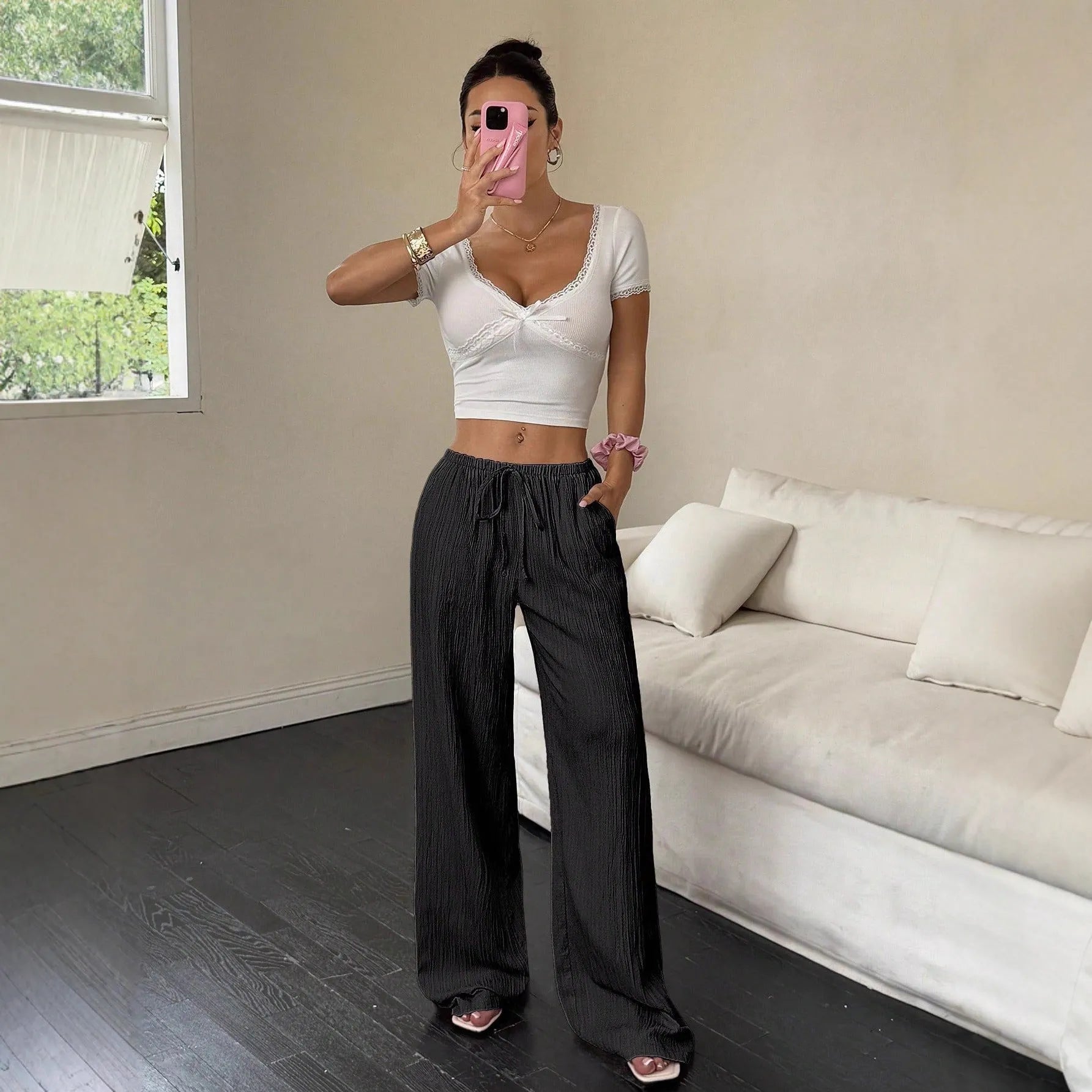 Women's black wide-leg trousers with a front lace-up detail on the waistband, laid flat.