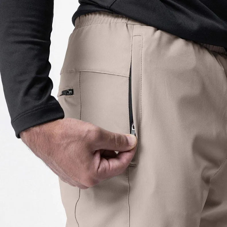 Man wearing dark grey tapered fitness trousers with adjustable ankle ties during a workout.