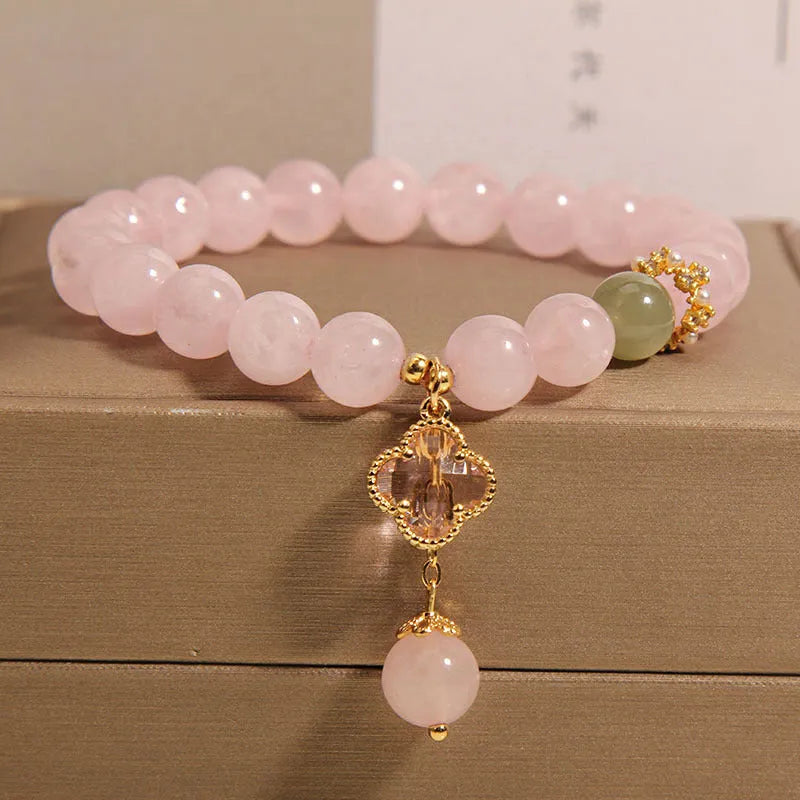 Pink crystal women's bracelet with four-leaf clover pendant charm and rhinestone decoration.