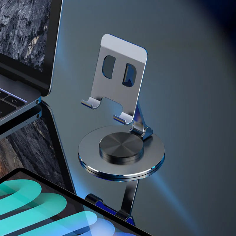 Aluminium alloy rotating mobile phone bracket in silver on a desk, showing three-axis joint and metal texture finish