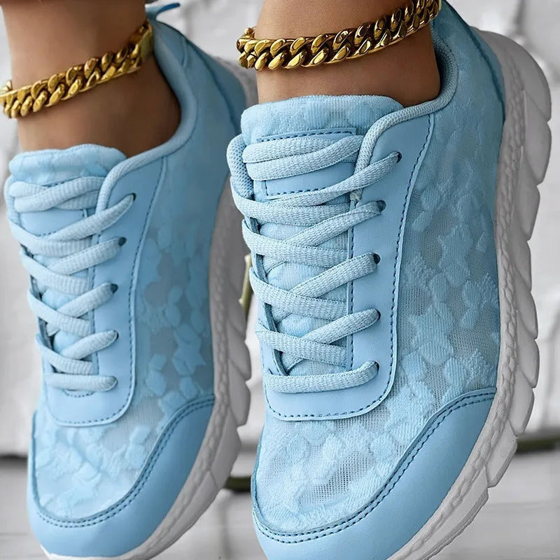Women's white canvas sports shoes with a flat heel and round toe on a plain background.