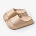 Women's beige fish mouth slippers with a thick light-coloured sole on a wooden floor.