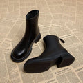 Women's black flat-heel ankle boots with round toe and back zipper.