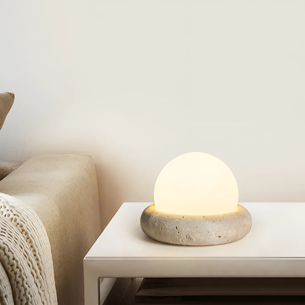Cream coloured modern bedside night lamp with remote control on a table.
