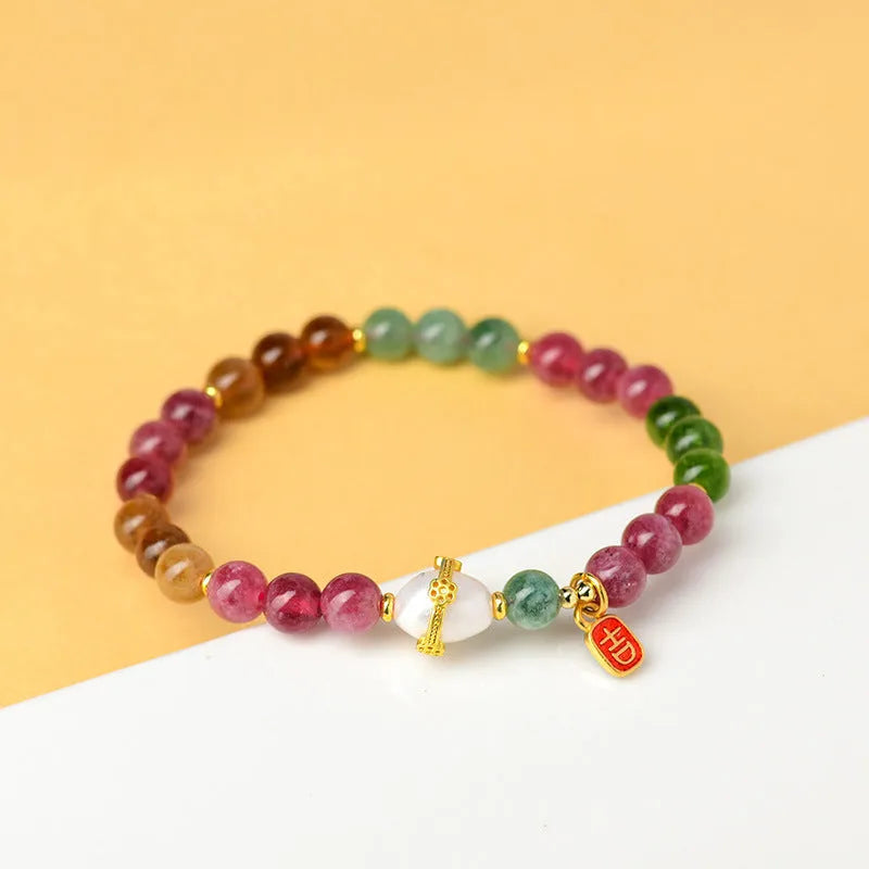 Geometric chalcedony stone bracelet with tourmaline colour beads on a wrist.