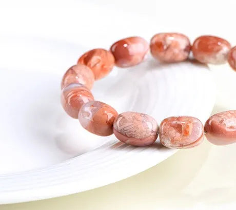 Natural cherry agate barrel bead bracelet with Ruyi symbols on a white background.