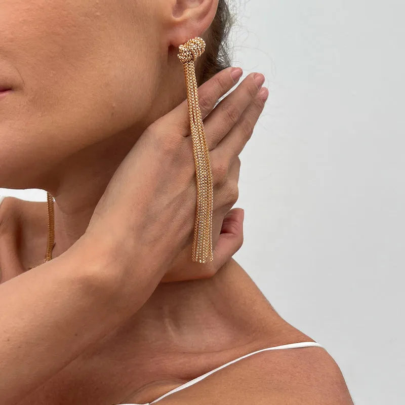 Simple Y-shaped metal tassel necklace in gold finish on a woman, with matching earrings, minimalist style for commuting wear