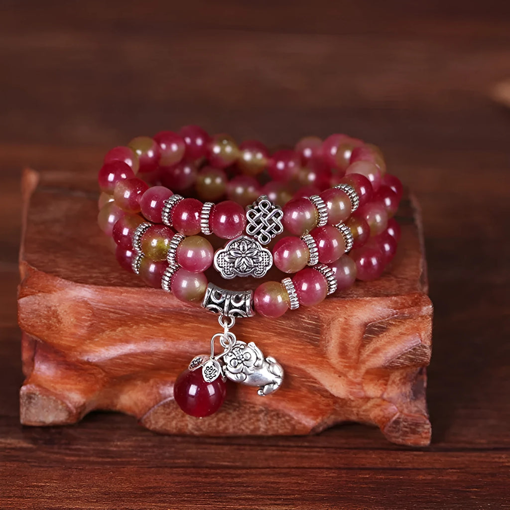 Handmade natural watermelon crystal bracelet with a Chinese knot, showing geometric beads in elephant style.