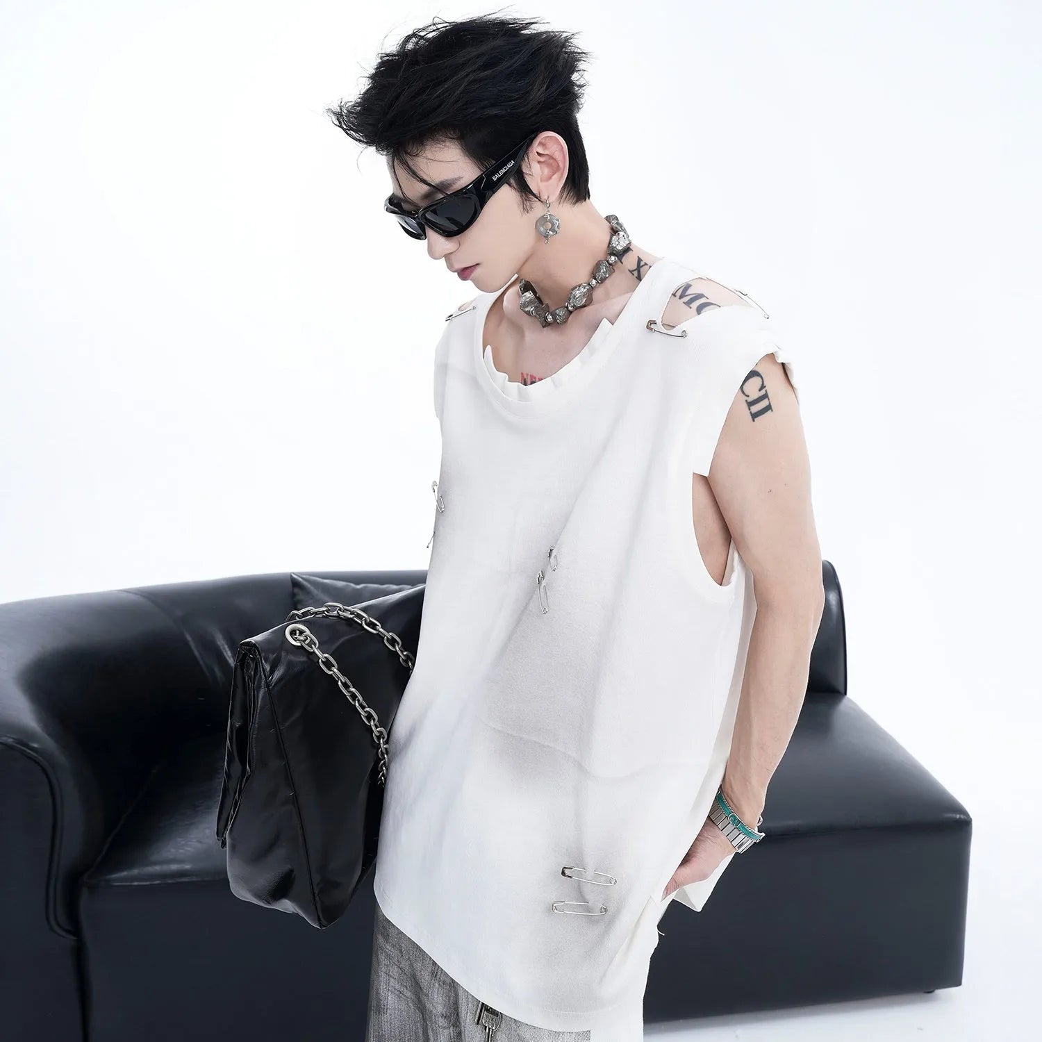 Man's black ripped irregular sleeveless vest t-shirt with asymmetric hem on a plain background.