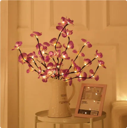 Pink Phalaenopsis-shaped LED decorative light with a bendable 65cm fabric branch on a wooden table.