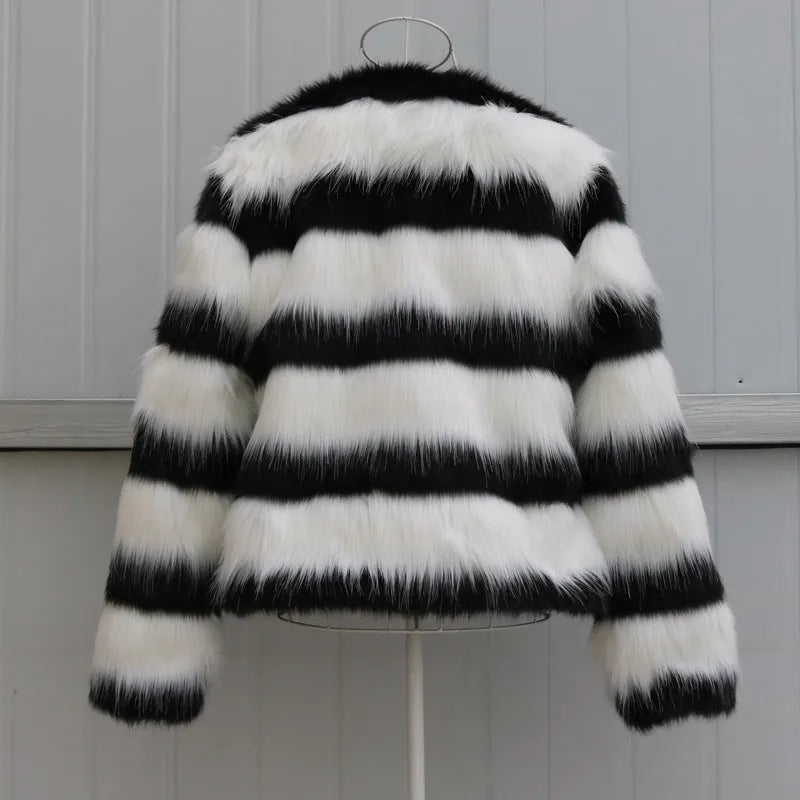 Long-sleeved black and white striped faux fur jacket for women on a grey background.