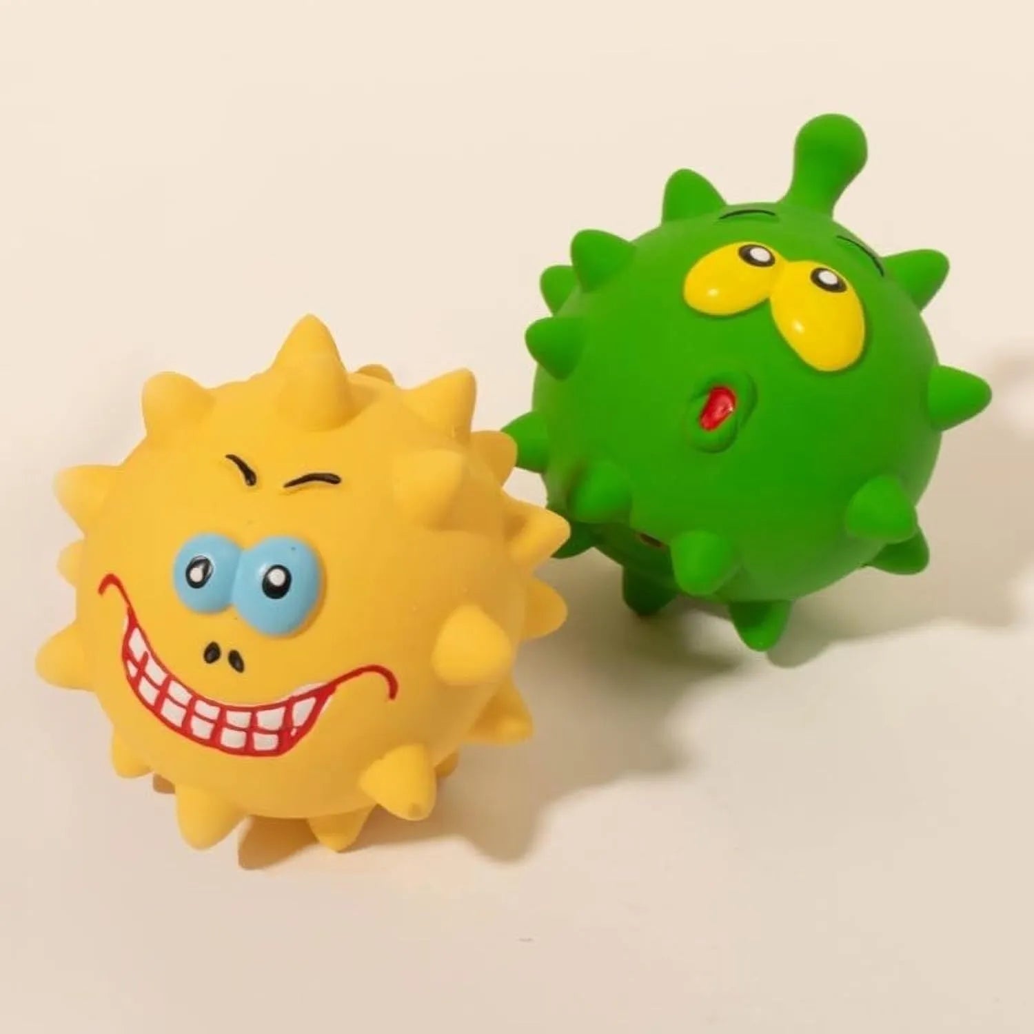 Set of four colourful squeaky dog balls with cute faces on a natural latex rubber texture.