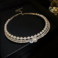 Close-up of a silver curved geometric alloy necklace for women, resting on a surface to show its clavicle chain shape.