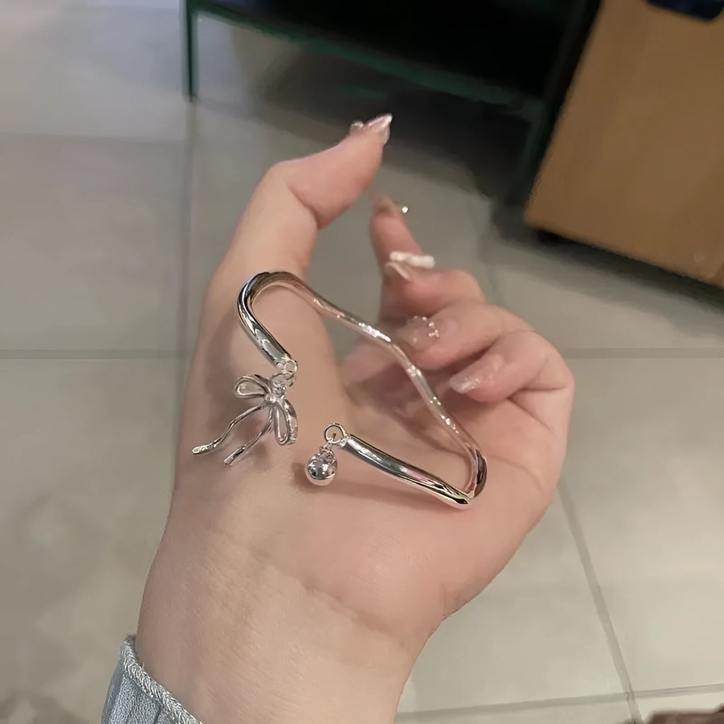 Silver adjustable bracelet with a large bow charm on a model's wrist, showing the sliding clasp.