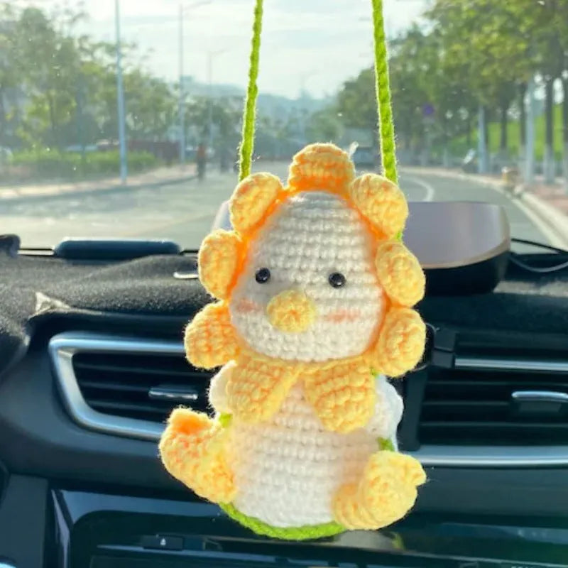 Green and white knitted wool car plant ornament hanging from a rope