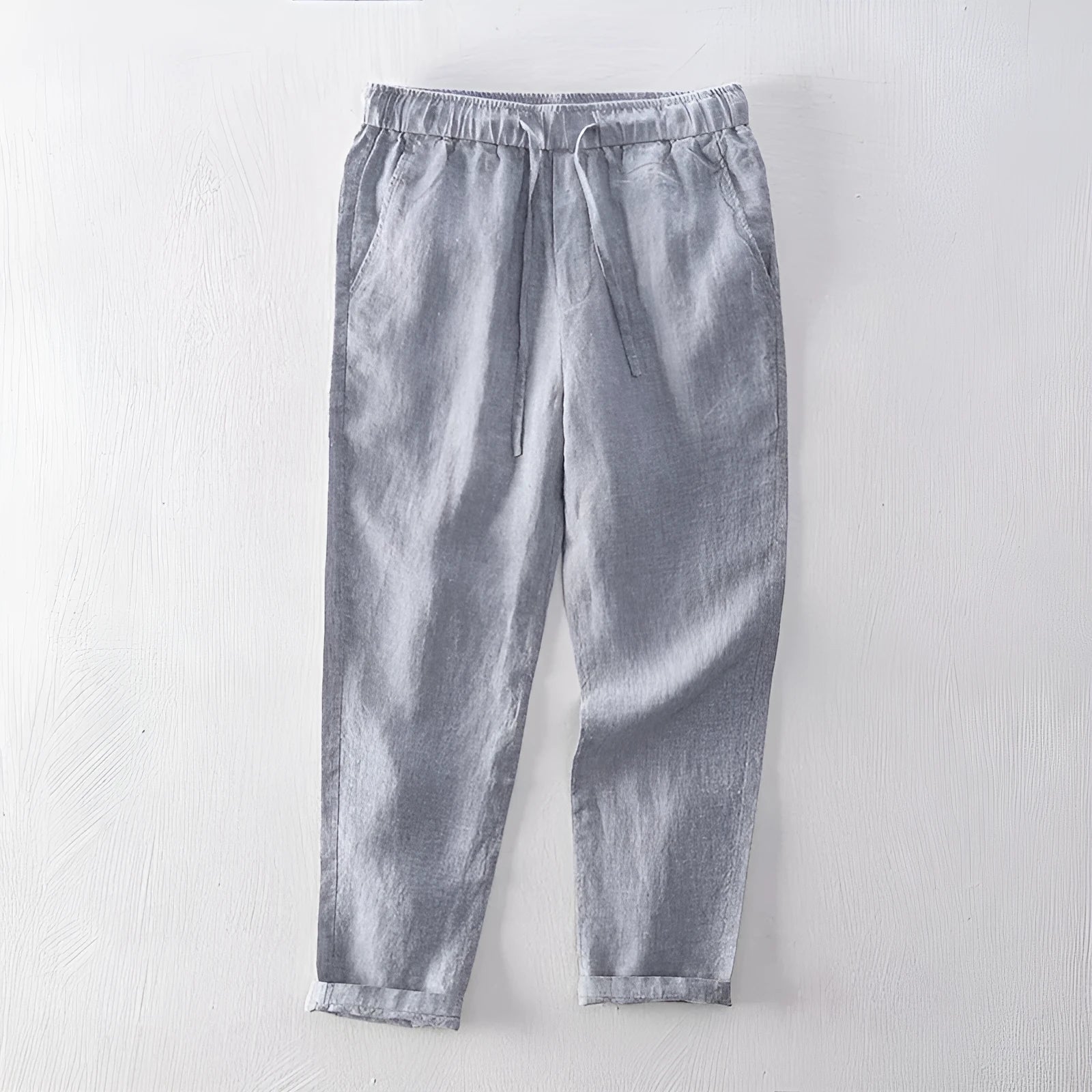 Men's straight leg linen trousers in light grey on a hanger.