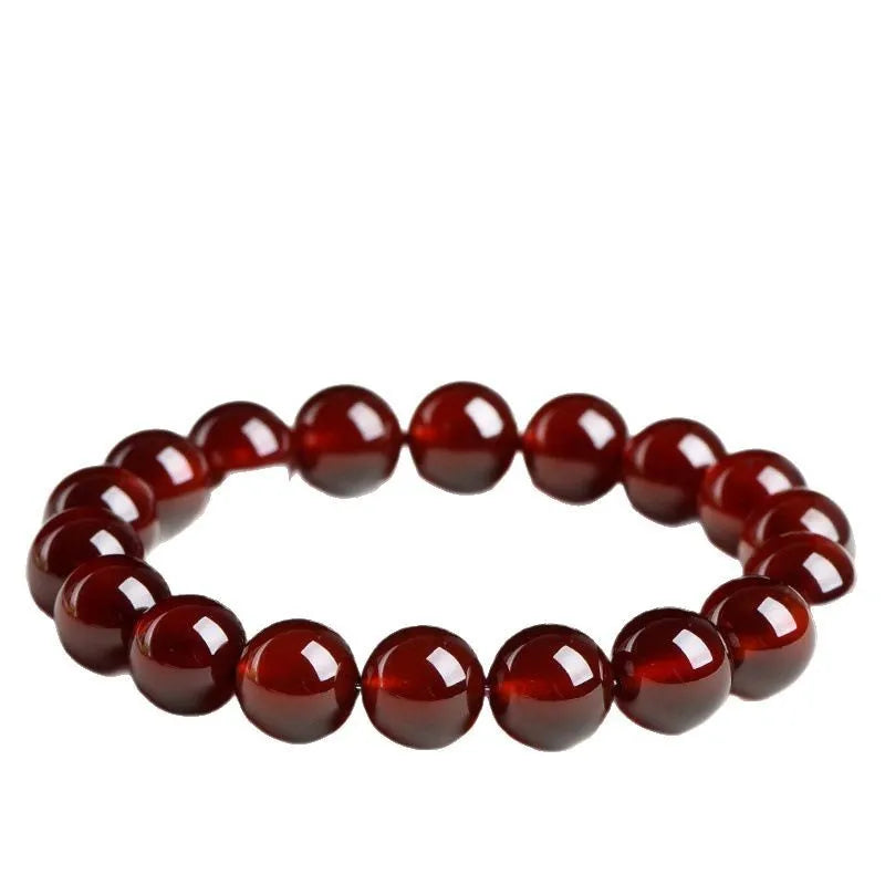 Natural orange red garnet crystal bracelet with ruyi design on a wrist.