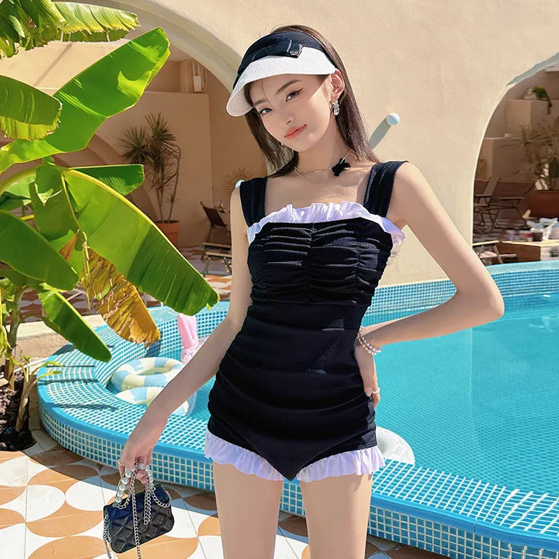Women's solid colour one-piece jumpsuit swimsuit with suspender straps in pink, green, or black.