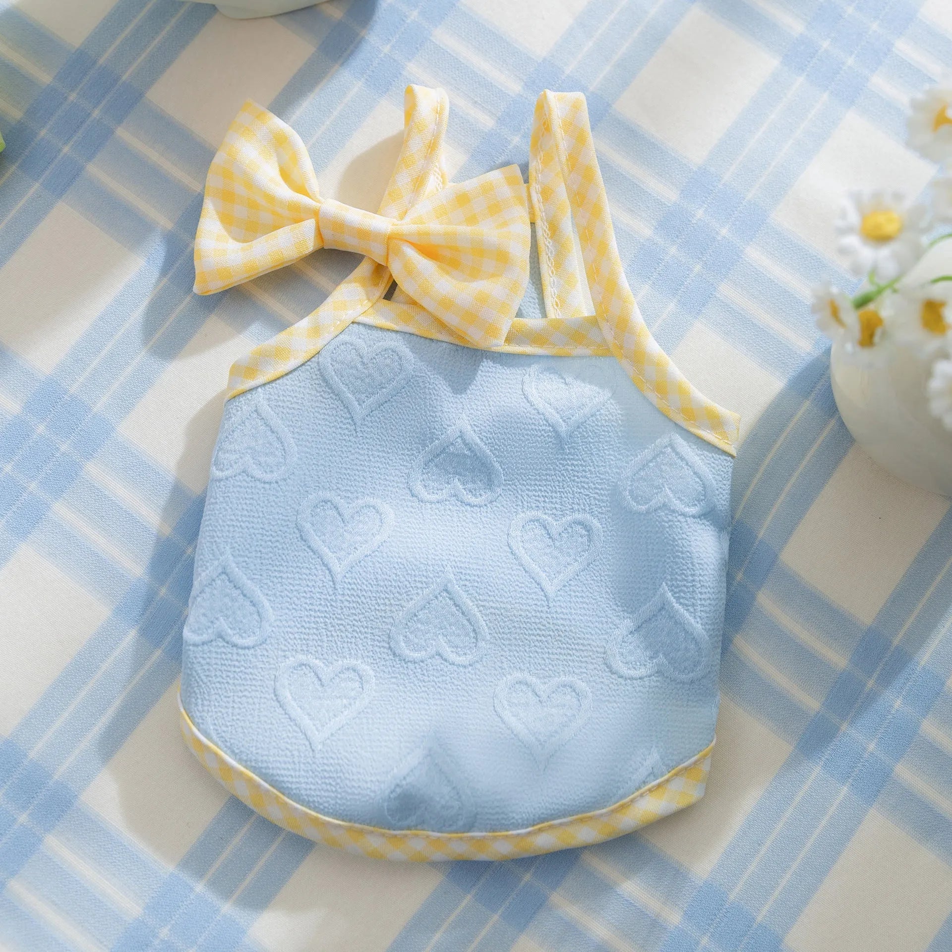 Small dog wearing a blue elastic vest with a heart texture and bow suspenders.