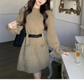 Women's beige loose knitted long sleeve dress with high waist and a black belt.