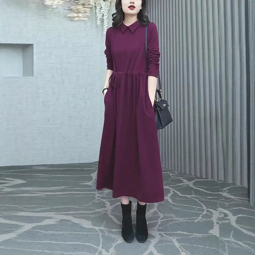 A woman wearing a solid purplish-red long-sleeve maxi dress with extra-long sleeves, suitable for autumn and winter.