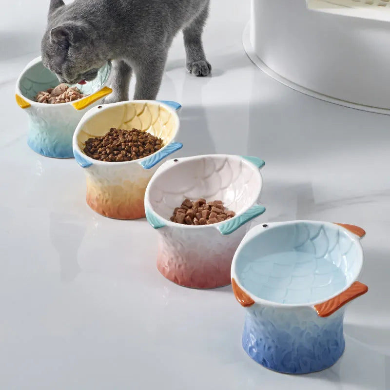 Blue ceramic fish-shaped cat bowl with tilted design and non-slip base on a wooden surface