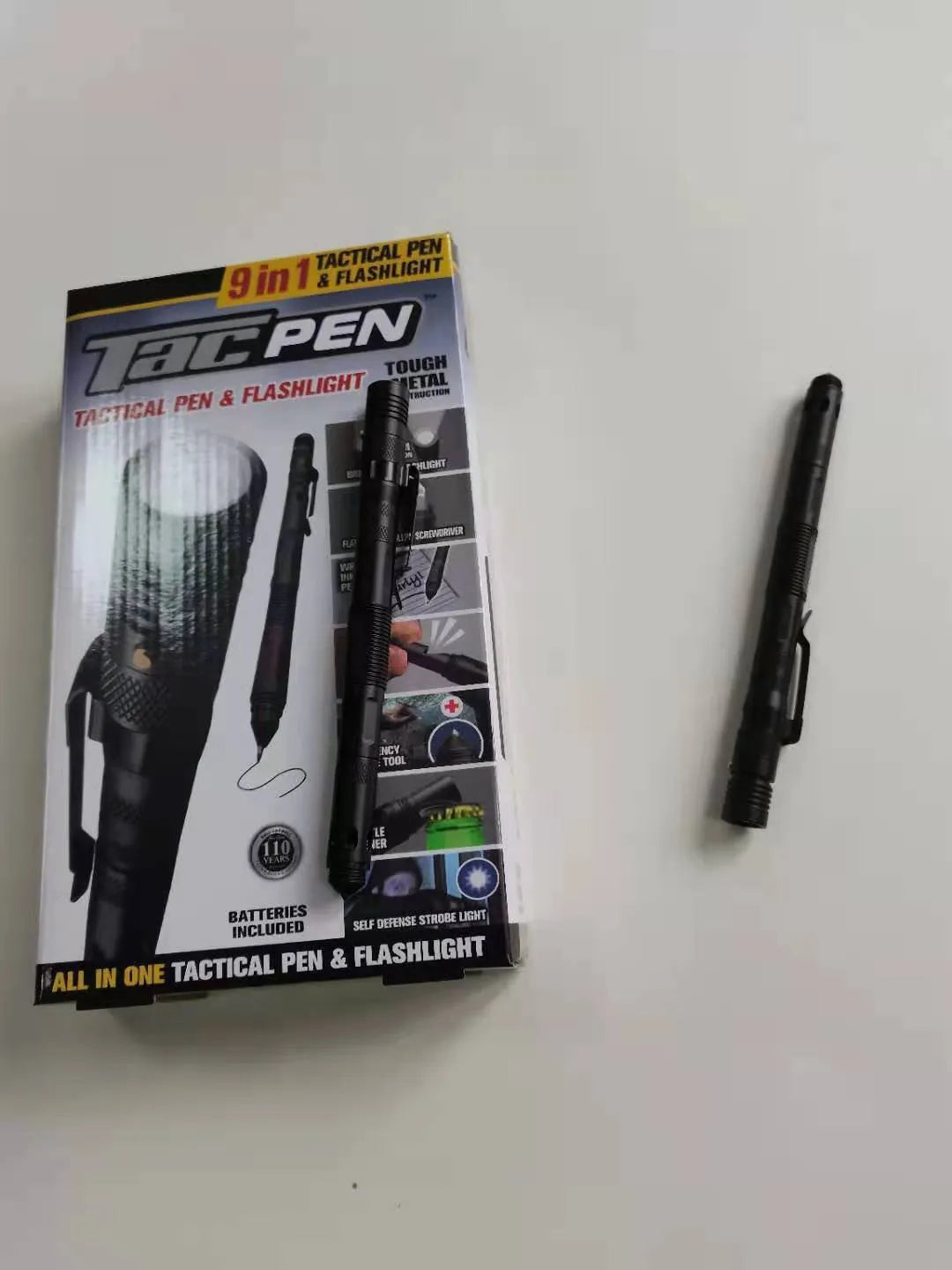 Black multi-function survival pen with built-in LED flashlight and pointed steel window breaker tip.