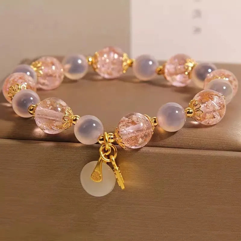 Close-up of a women's pink agate heart bracelet with a luminous glaze and a silver peace buckle clasp.