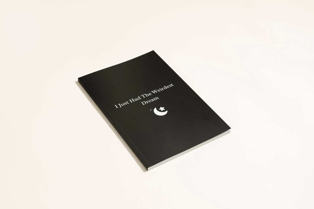 Black hardcover dream journal notebook with ruled pages open on a table.
