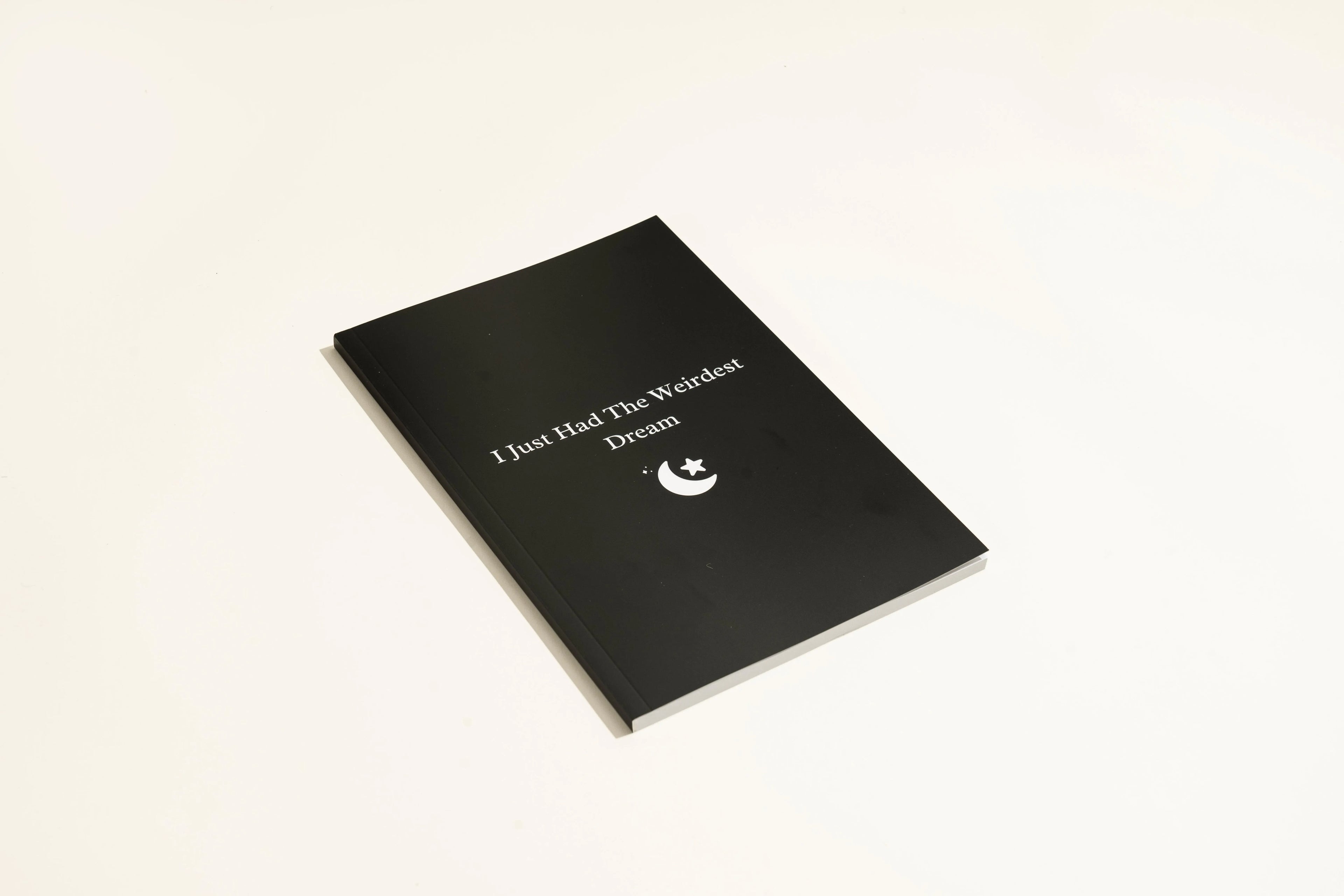 Black hardcover dream journal notebook with ruled pages open on a table.
