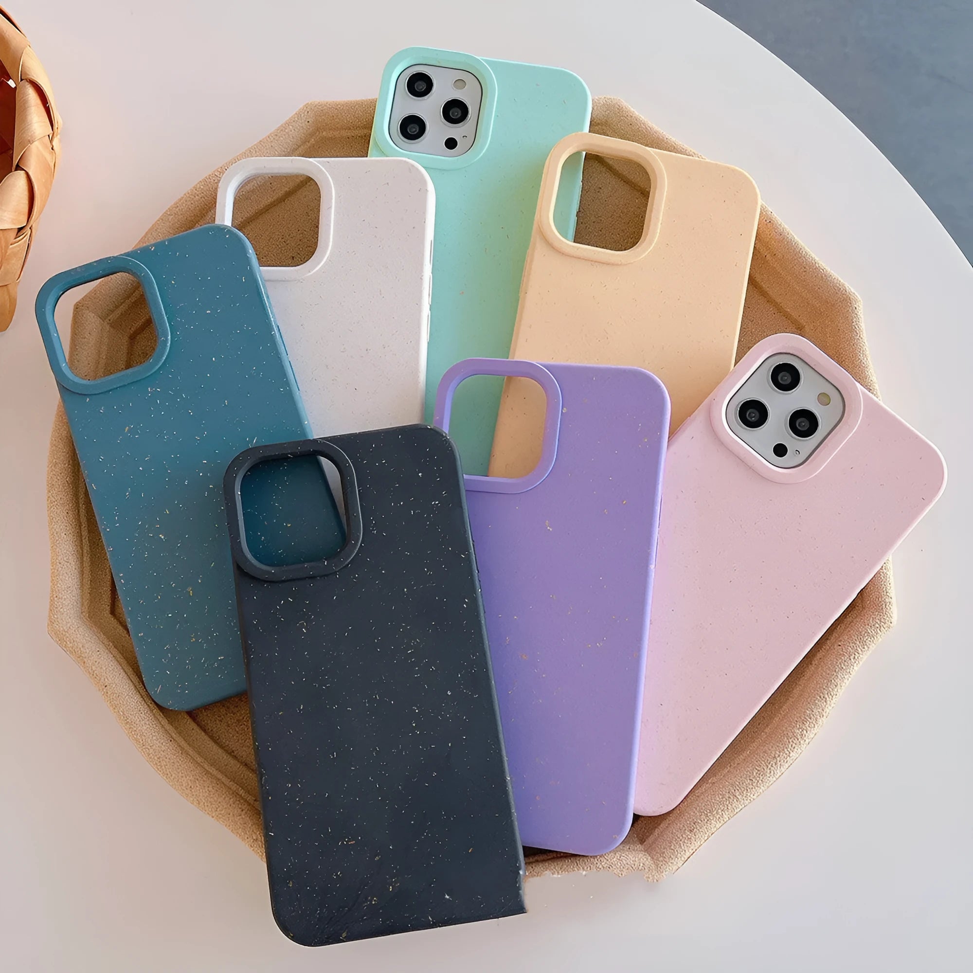 Biodegradable wheat straw mobile phone case for iPhone in seven colour options on a table.