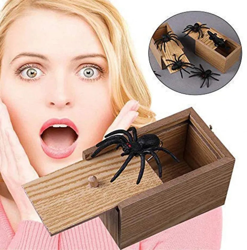 Wooden prank scare box with a lifelike spider figurine on a table.