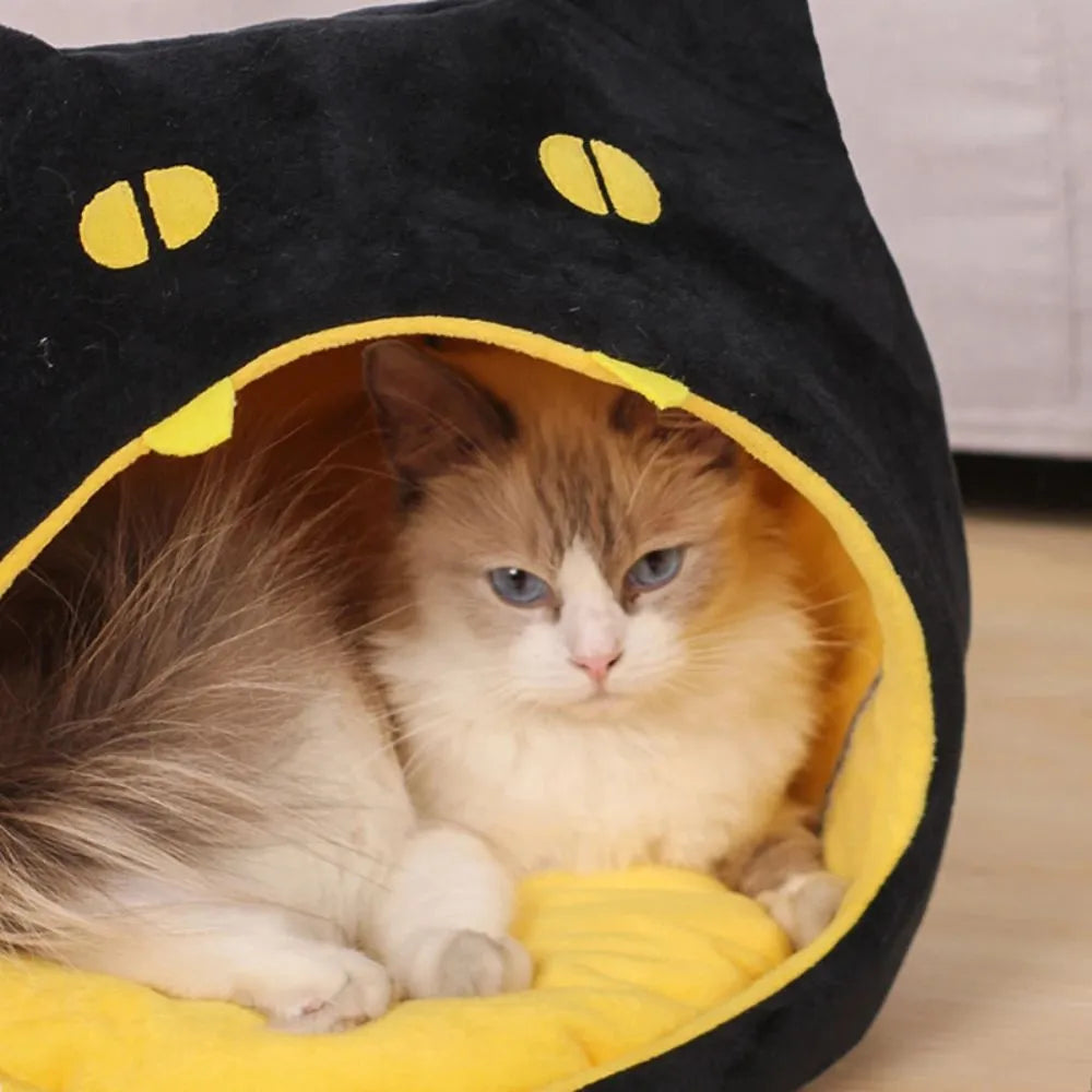Grey cat-shaped enclosed pet bed with a round opening, sitting on a wooden floor.