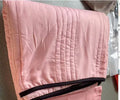 Lightweight seersucker summer quilt in various colours on a bed