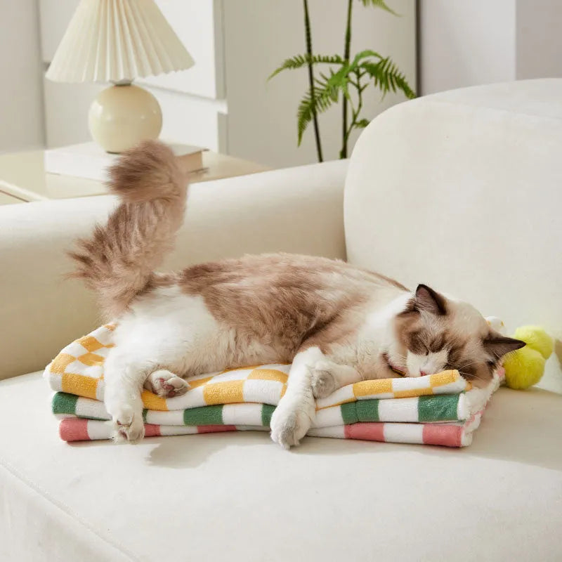 Plush pet blanket with plaid pattern and fur ball decoration for cats and dogs on sofa