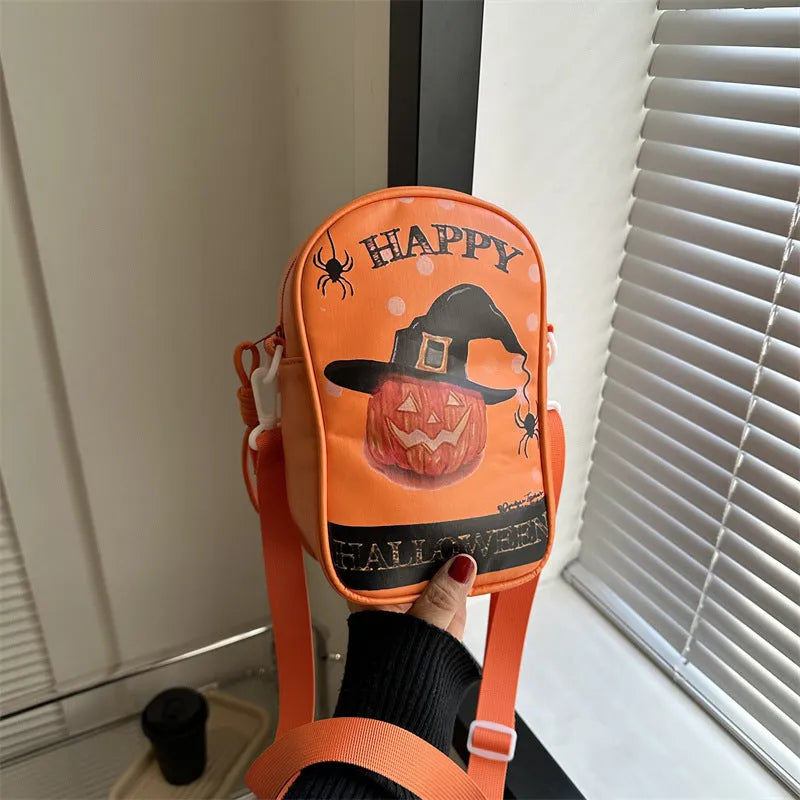 Black Halloween crossbody bag with orange pumpkin, white ghost, and bat graffiti print, shown worn across the body.