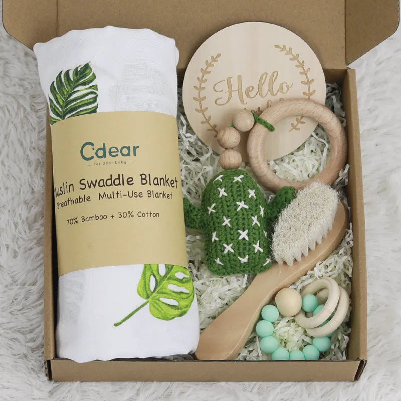 Baby teething toy gift set showing gauze blanket, wooden bell, gum teether, tire brush, and milestone on white background