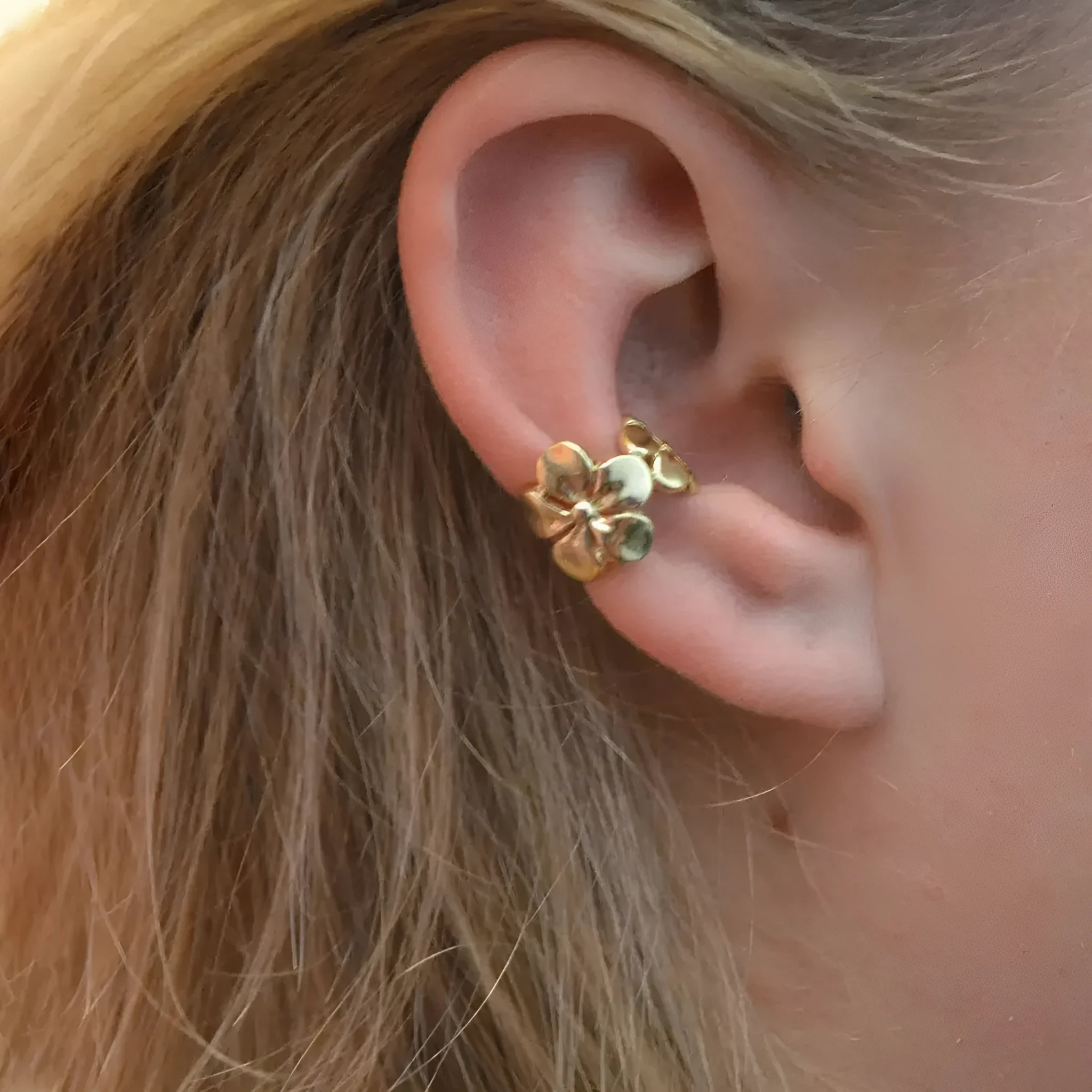 Gold coloured starfish and conch drop earrings on a white background.