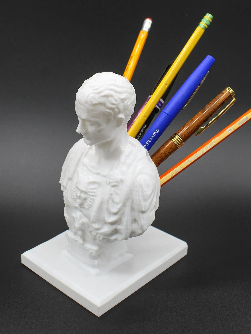 White synthetic resin pen holder with American character sculpture design for holding pens on a desk.