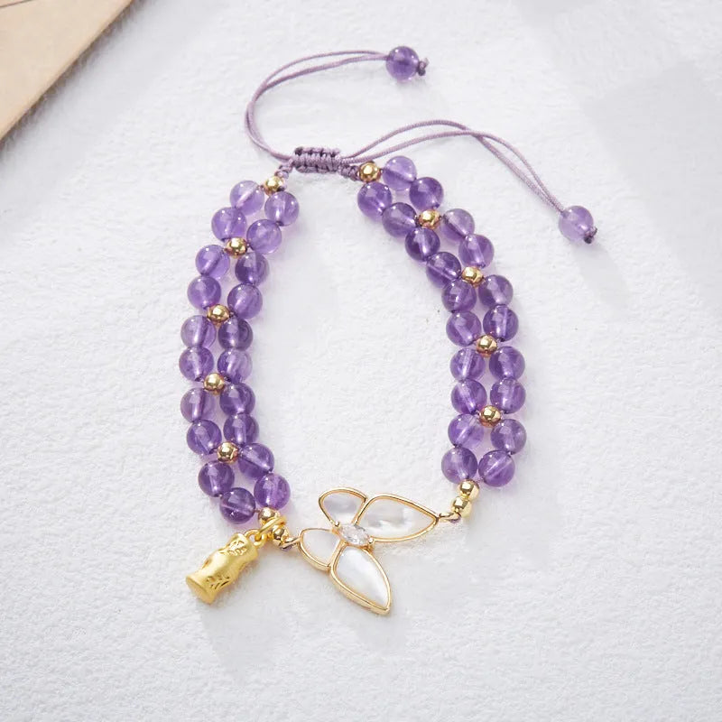Close-up of a women's woven bracelet with 6mm aquamarine beads and a butterfly charm on a wrist.