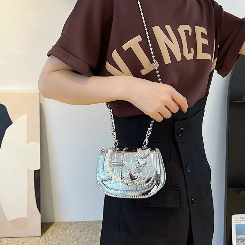 Silver women's PU leather mini tote saddle crossbody bag on a table.